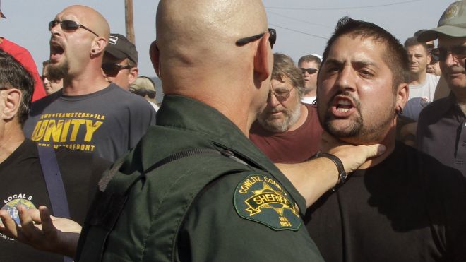 A Cowlitz County Sheriff grabs a union worker by the throat as police move in on several hundred union workers blocking a grain train in Longview, Wash., Wednesday, Sept. 7, 2011